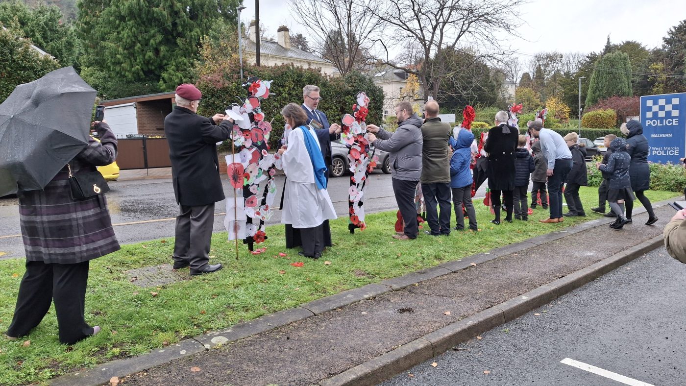 PCC John Campion and local schoolchildren pinning poppies on to statues outside Malvern police station