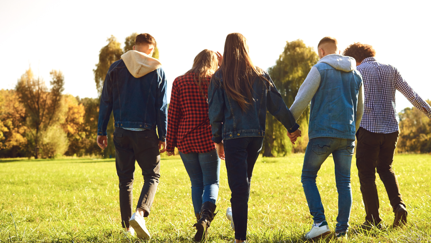 A group of young people walking over a green field