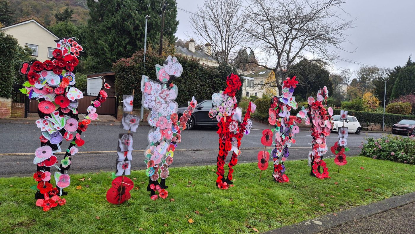 Image shows several 'Unknown Tommy' statues covered in poppies standing outside Malvern Police Station in 2025