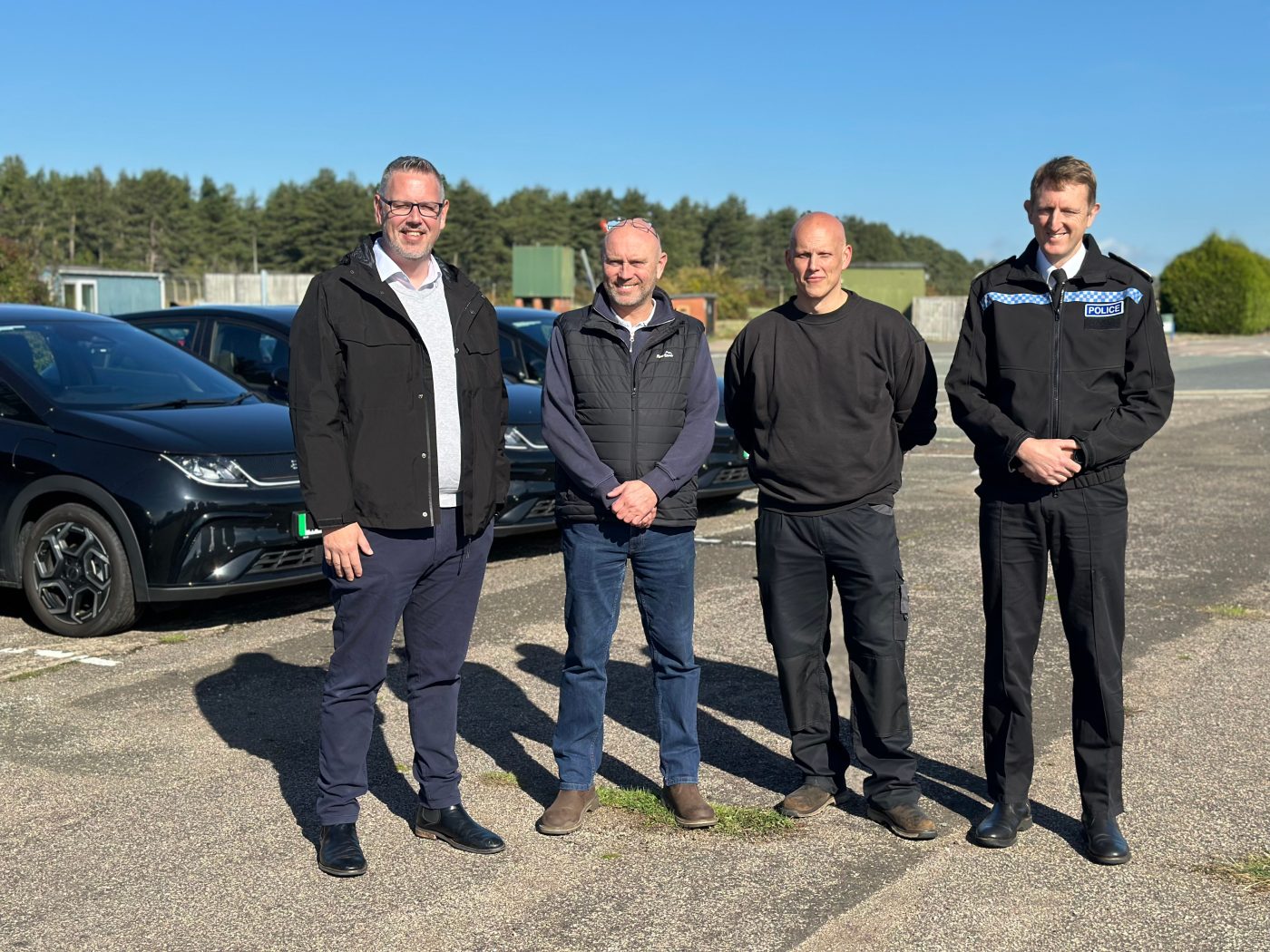 Four men next to Electric Vehicles